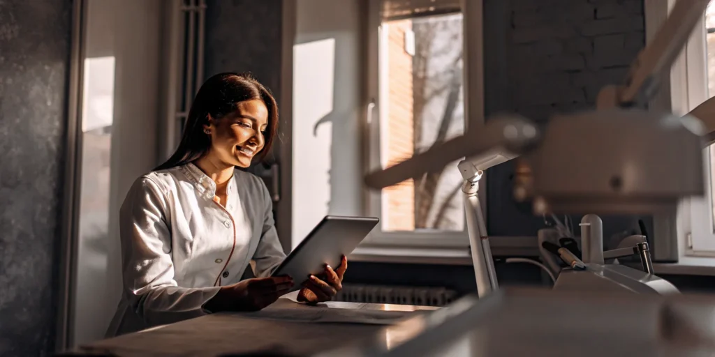 Dentist reviewing financial reports on a tablet in a modern dental office